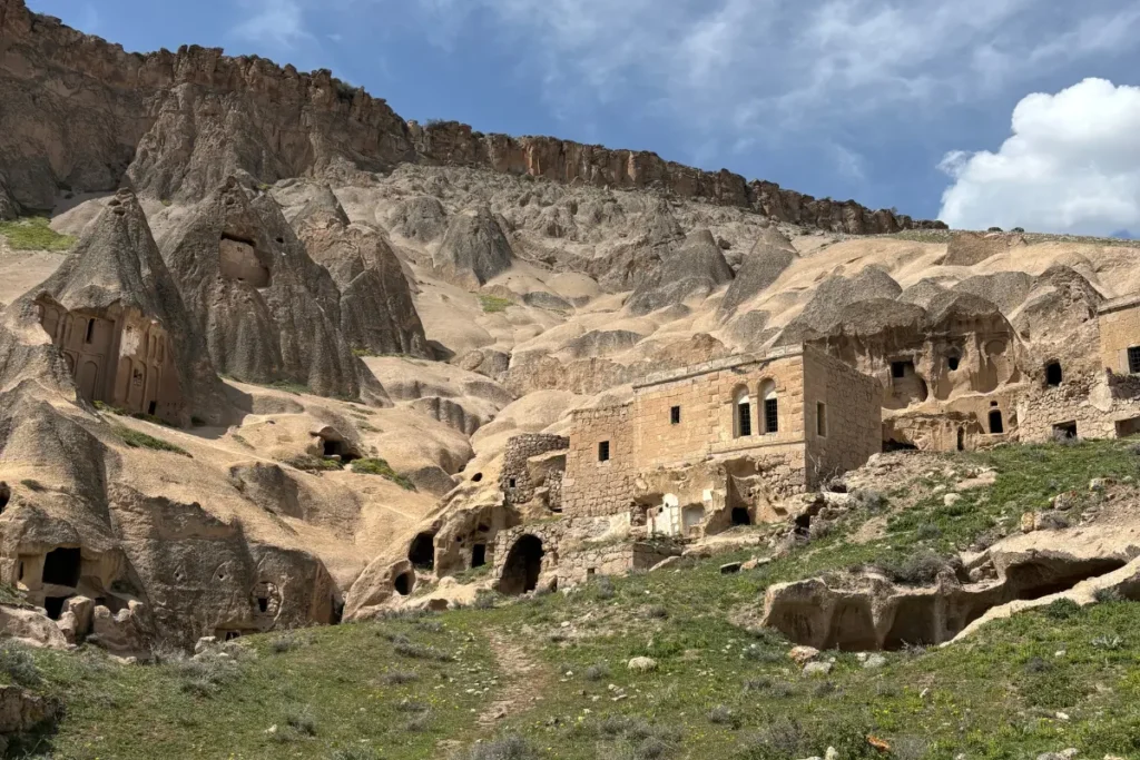 Selime Monastery7 Wide horizontal view of the rear cliff face showing numerous rock-cut rooms, windows, and carved openings.