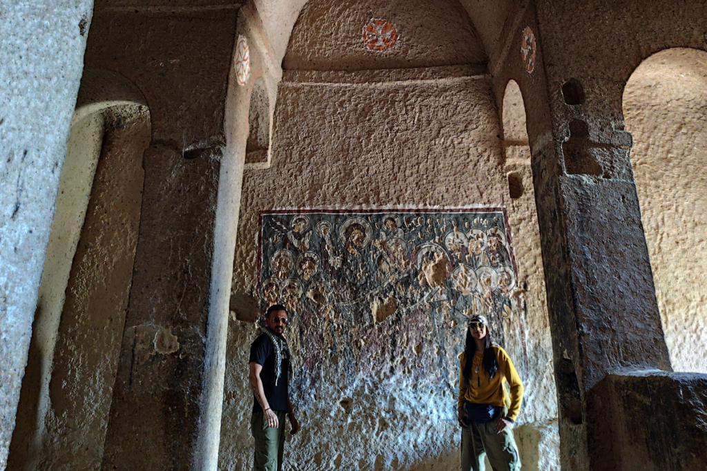 Selime Monastery9 Interior of an ancient rock-cut church showing faded frescoes and colorful religious paintings preserved on the stone walls and archways.