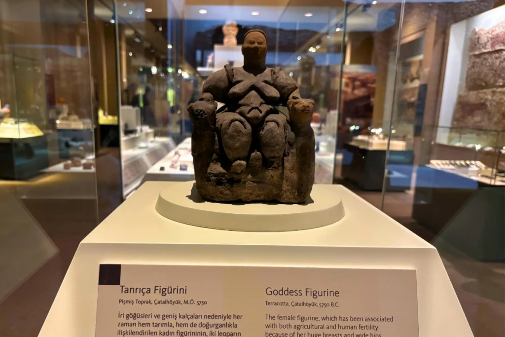 idol 7 Seated Mother Goddess terracotta figurine from Çatalhöyük displayed inside a museum glass case alongside informational signage.